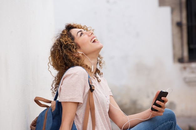 Rire jeune femme avec un téléphone portable et des écouteurs