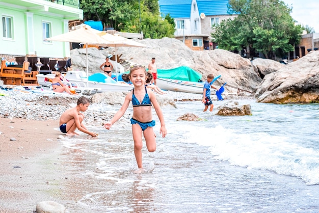 Rire joyeuse petite fille fuyant les vagues sur la plage près de la mer