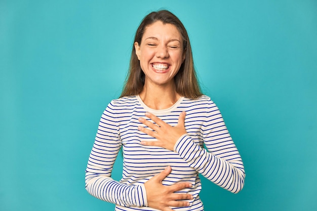 Rire joyeusement et s'amuser en gardant les mains sur le ventre