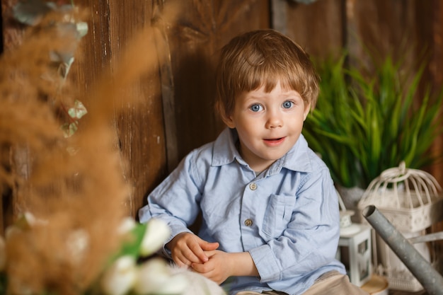 Photo rire petit garçon jouant avec le lapin de pâques dans une herbe verte. décoration rustique. fond en bois