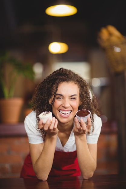 Rire serveuse montrant deux cupcakes