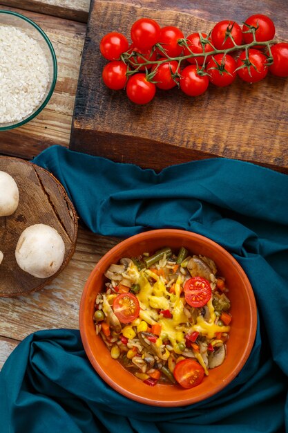 Risotto aux champignons dans une assiette sur un fond en bois sur une serviette bleue et des ingrédients.