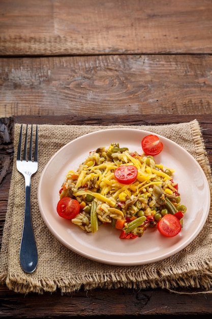 Risotto aux champignons dans une assiette sur un fond en bois sur une serviette en lin et une fourchette.