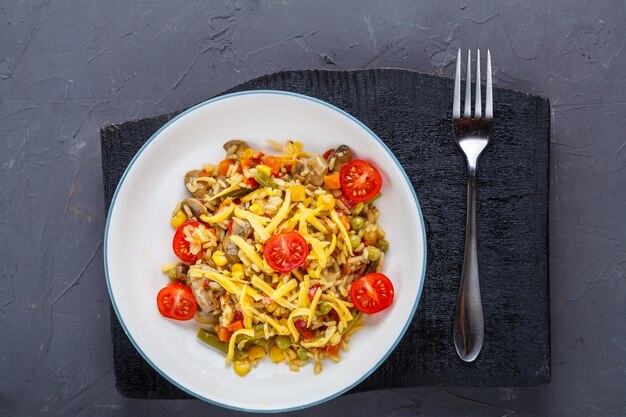 Risotto aux champignons dans une assiette sur fond gris sur des sous-verres noirs et une fourchette. photo horizontale