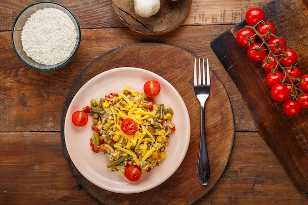 Risotto aux champignons et fromage sur un fond en bois près du riz et des légumes.