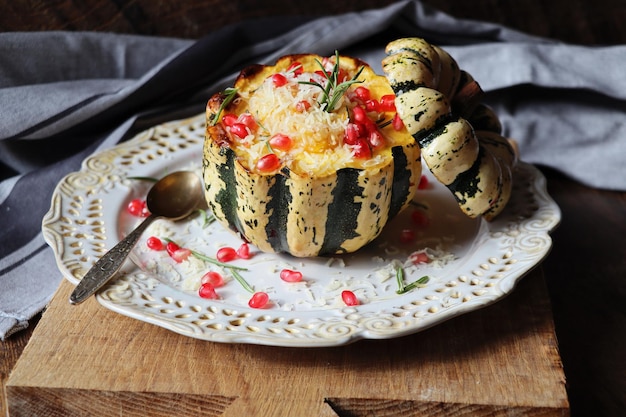 Risotto de citrouille servi dans une citrouille creusée citrouille cuite au four avec du fromage et des graines de grenade