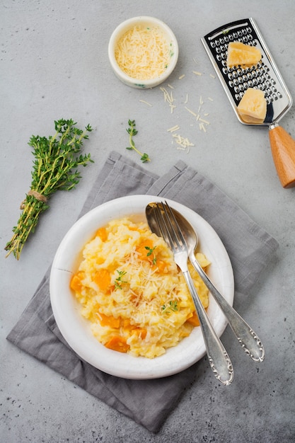 Risotto à la citrouille avec thym, ail, parmesan et vin blanc sur béton gris ou surface en pierre. Mise au point sélective. Style rustique.