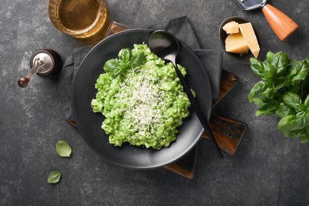 Risotto italien Délicieux risotto avec sauce au pesto ou pesto à l'ail sauvage basilic parmesan et verre de vin blanc sur fond de table en ardoise sombre Dîner italien Vue de dessus avec espace de copie