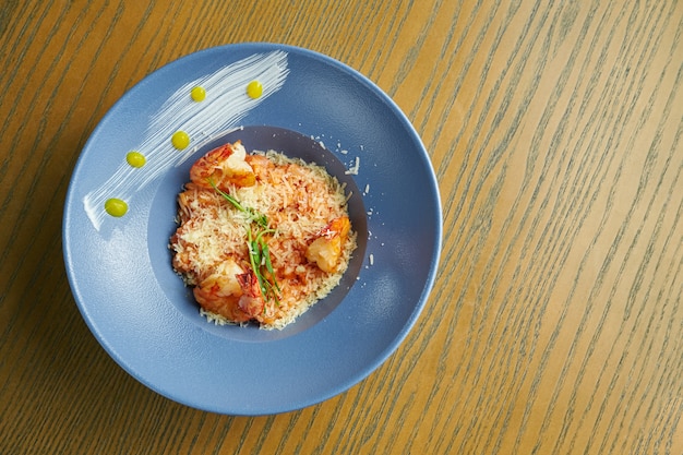 Risotto de riz aux crevettes. Riz aux fruits de mer dans un bol bleu contre une surface en bois. cuisine italienne