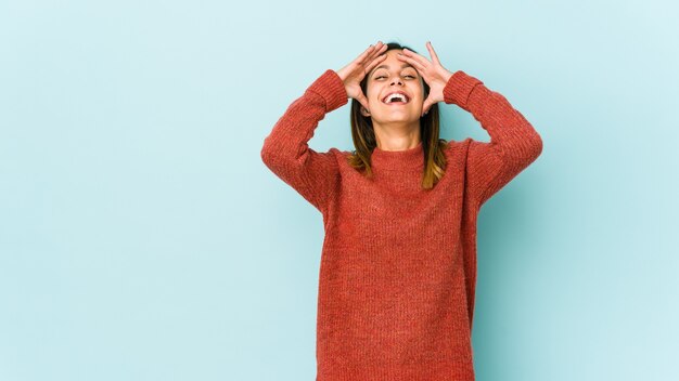 rit joyeusement en gardant les mains sur la tête. Concept de bonheur.