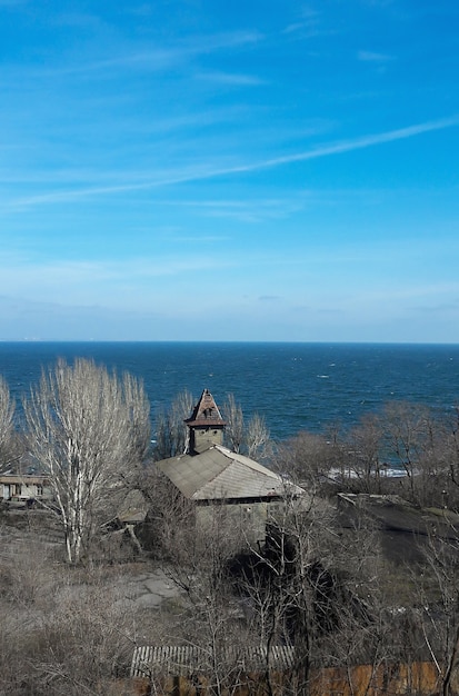 Sur le rivage de la mer froide, il y a une vieille maison en bois avec des bâtiments en arrière-plan