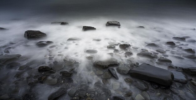 Rivage rocheux entouré par la mer avec une longue exposition sur un jour sombre