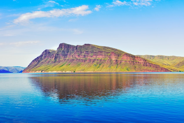 Un rivage vert sous un ciel bleu roches rouges au loin Territoire de Krasnoïarsk Sibérie Russie