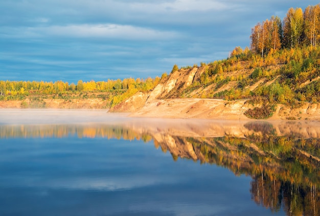 La rive du lac brumeux au petit matin éclairée