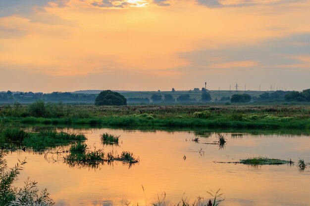 Rivière au coucher du soleil contre le ciel orange dramatique. Paysage de rivière au soir d'été