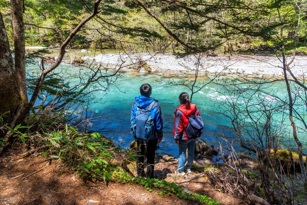 Photo rivière azusa de couleur turquoise à kamikochi dans les alpes du nord du japon avec un homme et une femme.