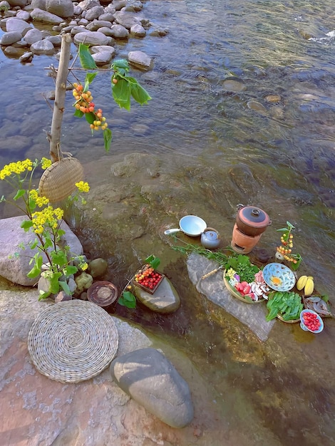 Une rivière avec un bouquet de fleurs et un fruit et un pot d'eau