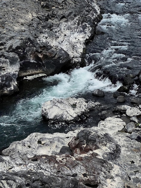 Une rivière avec une cascade et des rochers au premier plan.