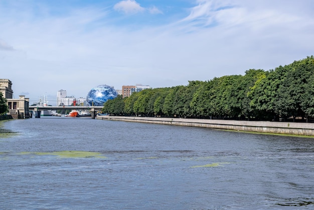 Une rivière dans la partie touristique de la ville avec des berges renforcées par des clôtures en béton et un parc avec des cimes d'arbres verdoyants