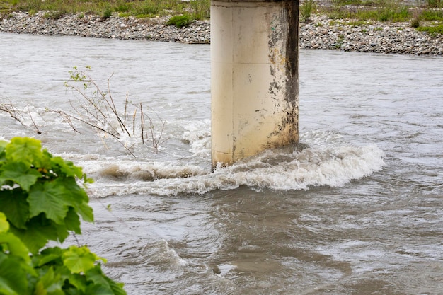 Une rivière déchaînée et des branches d'arbres coincées au support du pont après de fortes pluies et un ouragan