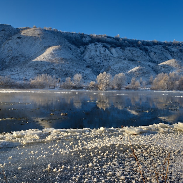 Rivière gelée depuis les rives vallonnées et les grandes banquises. Une journée ensoleillée avec un ciel sans nuages.