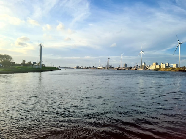 Une rivière avec un grand plan d'eau et une grande éolienne en arrière-plan.