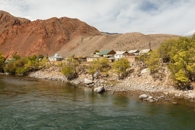 Rivière Kokemeren, maisons au bord de la rivière dans le village d'Aral, district de Jumgal de la région de Naryn au Kirghizistan