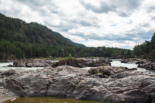 Une rivière de montagne à débit rapide, large et plein. De gros rochers sortent de l'eau.