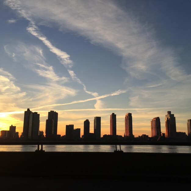 Photo rivière par des bâtiments modernes dans la ville contre le ciel au coucher du soleil