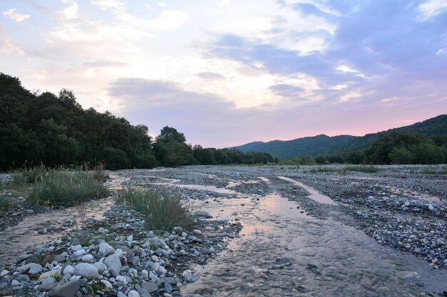 Une rivière avec des rochers et un ciel avec des nuages