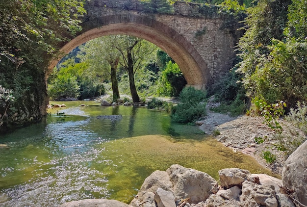 Rivière sauvage avec un vieux pont en arc de pierre en italie