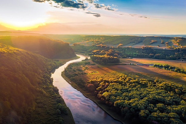 Une rivière traverse une vallée sur laquelle se couche le soleil.