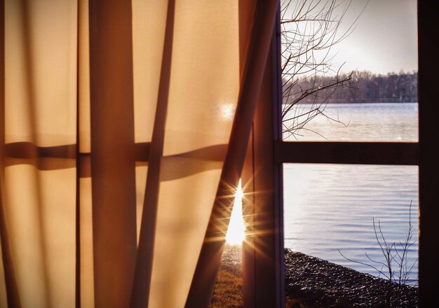 Photo rivière vue à travers une fenêtre avec rideau