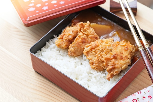 Riz au curry japonais garni de poulet frit et de légumes avec des baguettes