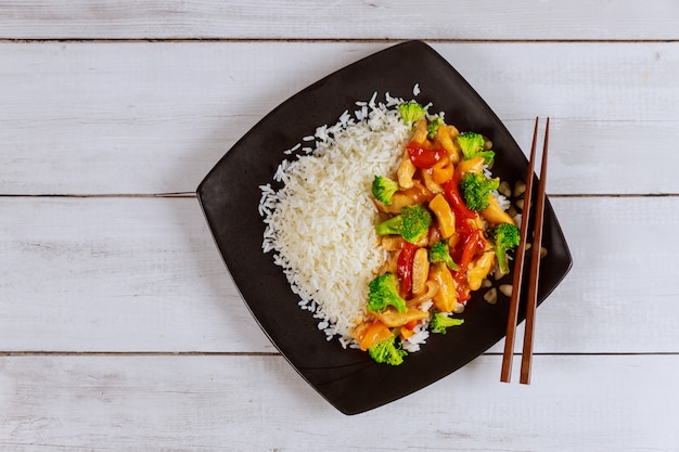 Riz au poulet sauté et légumes sur plaque carrée noire Cuisine chinoise.