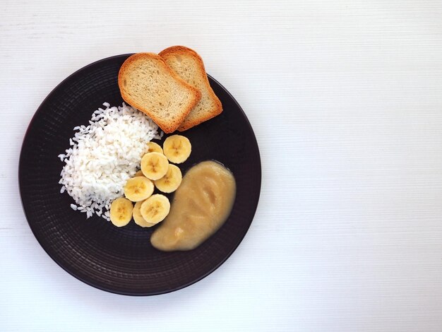 Riz aux bananes compote de pommes et pain grillé sur une assiette sombre Espace de copie