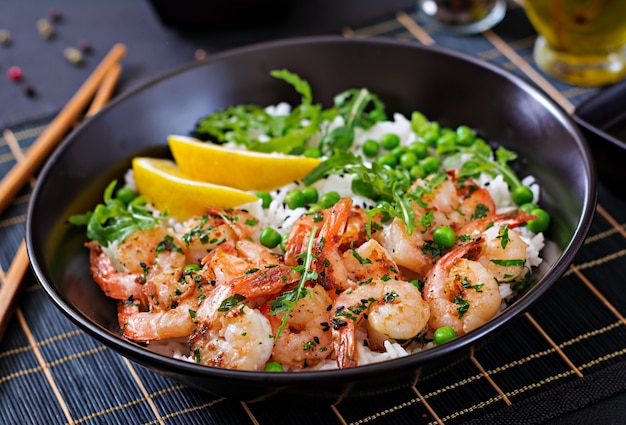 Riz aux petits pois verts, crevettes et roquette dans un bol noir. La nourriture saine. Bol de Bouddha.