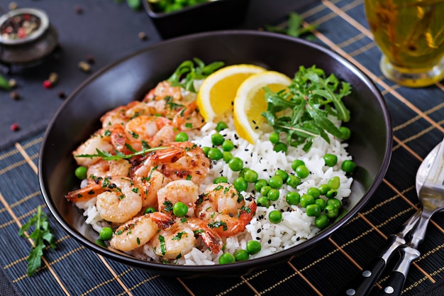 Riz aux petits pois verts, crevettes et roquette dans un bol noir. La nourriture saine. Bol de Bouddha.