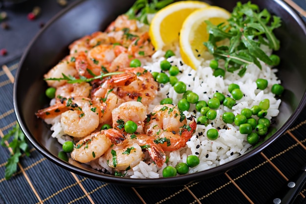 Riz aux petits pois verts, crevettes et roquette dans un bol noir. La nourriture saine. Bol de Bouddha.