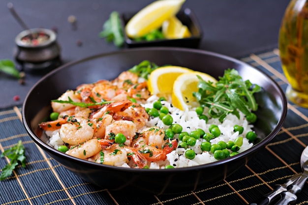 Riz aux petits pois verts, crevettes et roquette dans un bol noir. La nourriture saine. Bol de Bouddha.
