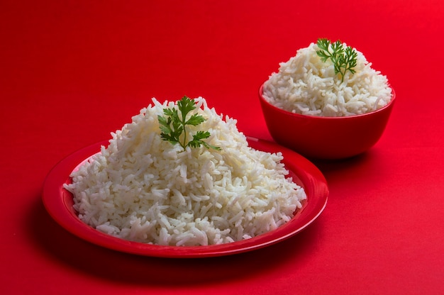 Riz basmati blanc cuit dans un bol et une assiette sur le rouge