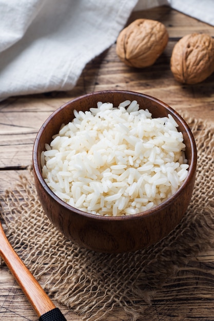 Riz bouilli blanc dans un bol en bois. Style rustique.