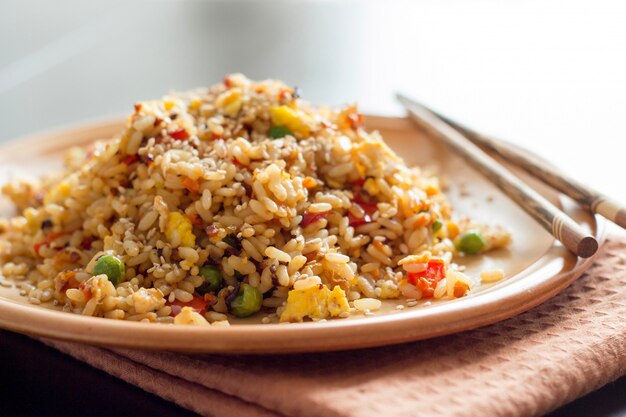 Riz chinois frit avec des légumes et des œufs avec des baguettes bouchent