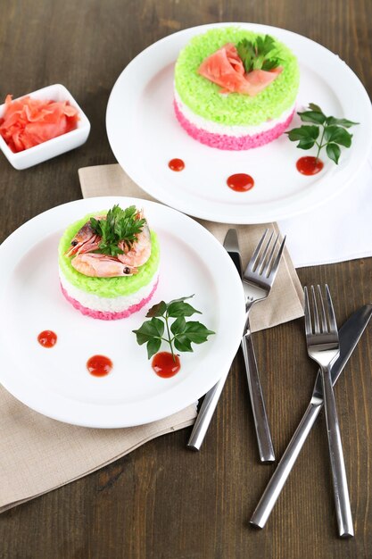 Riz coloré sur des assiettes sur des serviettes sur une table en bois