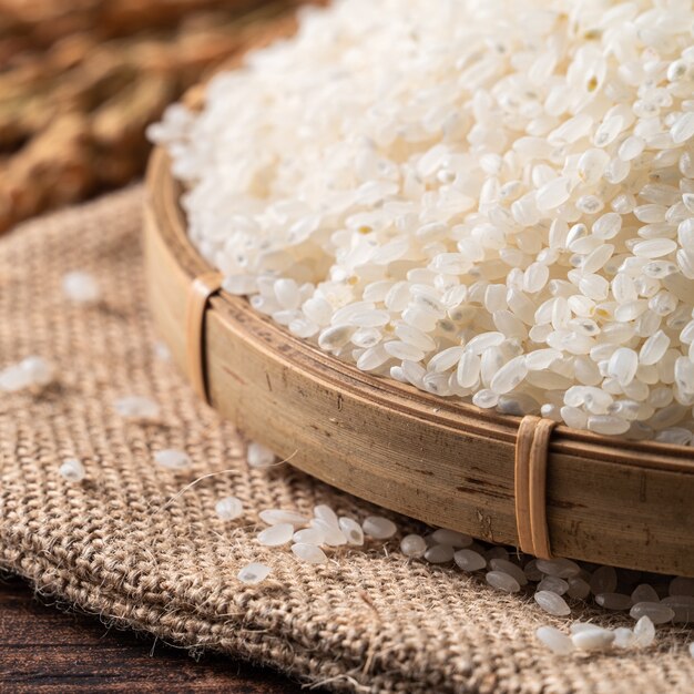 Riz comestible frais poli blanc cru sur fond de table en bois dans un bol, concept de design organique.