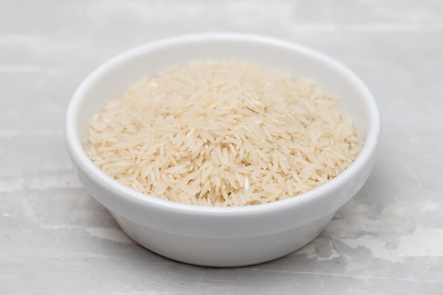 Riz cru sur bol blanc sur céramique grise