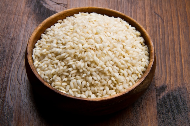 Riz cru dans un bol en bois sur une table en bois