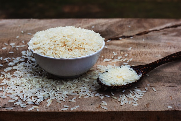 Riz à la cuillère en bois et tasse blanche sur une table en bois.