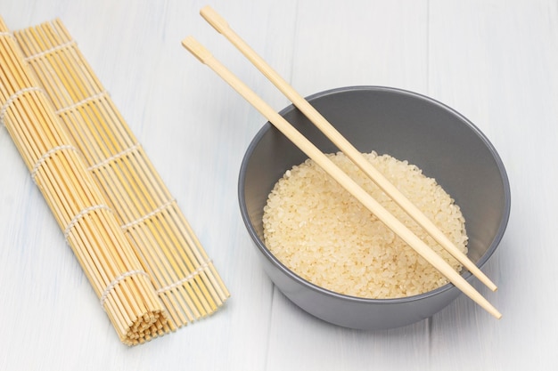 Riz dans un bol gris Baguettes sur un bol Tapis à sushi en bambou