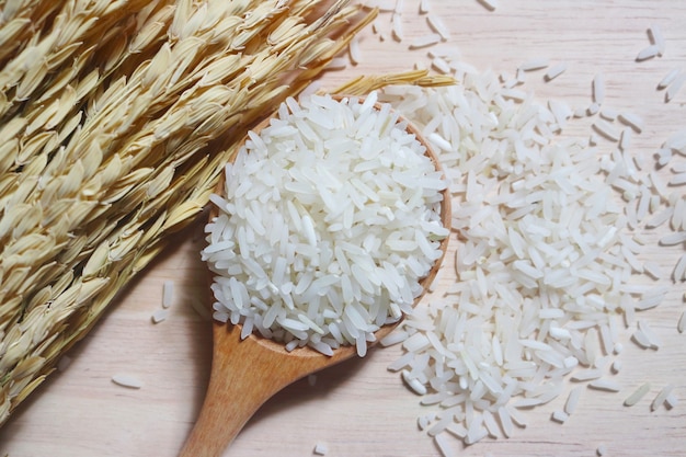 Riz dans une cuillère en bois avec paddy sur table en bois